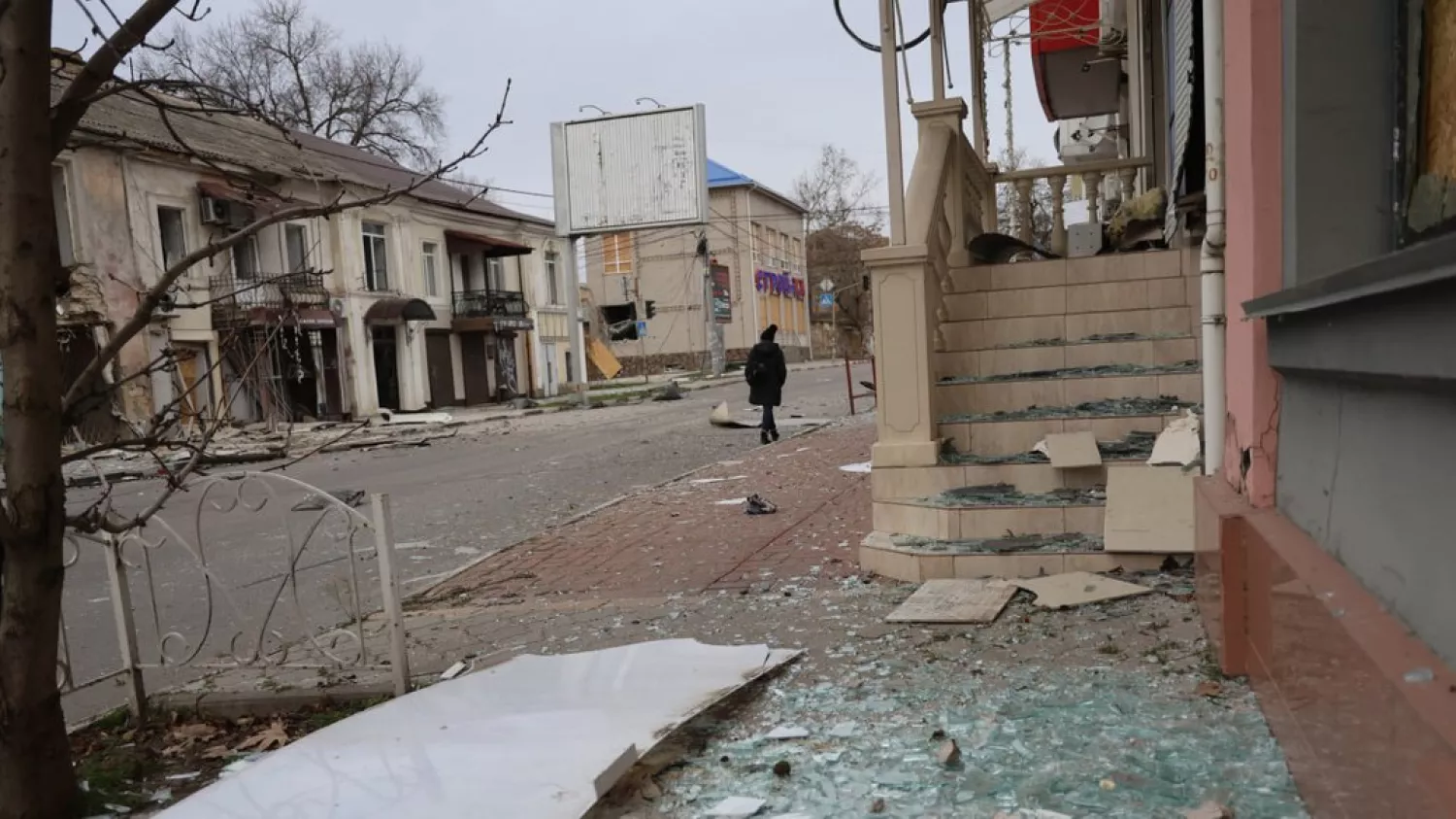 Жінка йде повз пошкоджений внаслідок російських ударів житловий квартал у Херсоні, грудень 2025 року. Фото: Суспільне Херсон