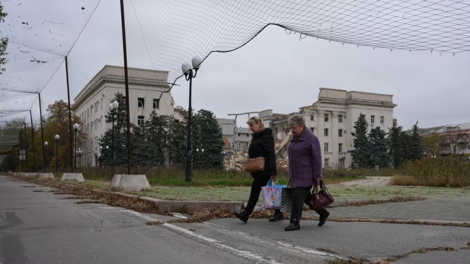 Жінки йдуть площею Свободи повз зруйновану авіабомбами будівлю Херсонської обласної адміністрації у перший день режиму тиші на Херсонщині для проведення гуманітарної операції в окупованих Олешках, 27 жовтня 2026 року. Фото: Іван Антипенко