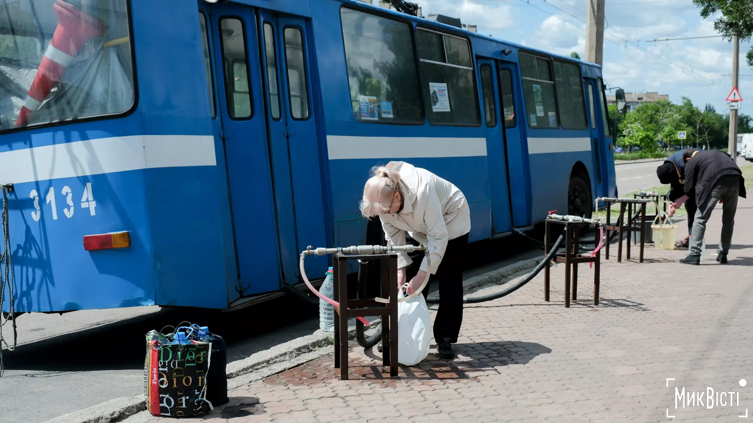 Жінка набирає воду з тролейбусу-точки видачі води, травень 2025 року. Фото «НикВести»